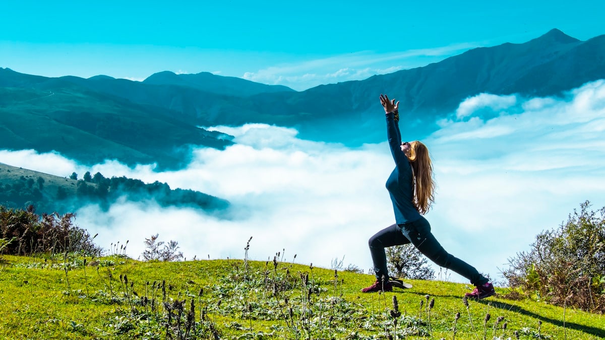 woman in black tank top and black leggings doing yoga on green grass field during daytime